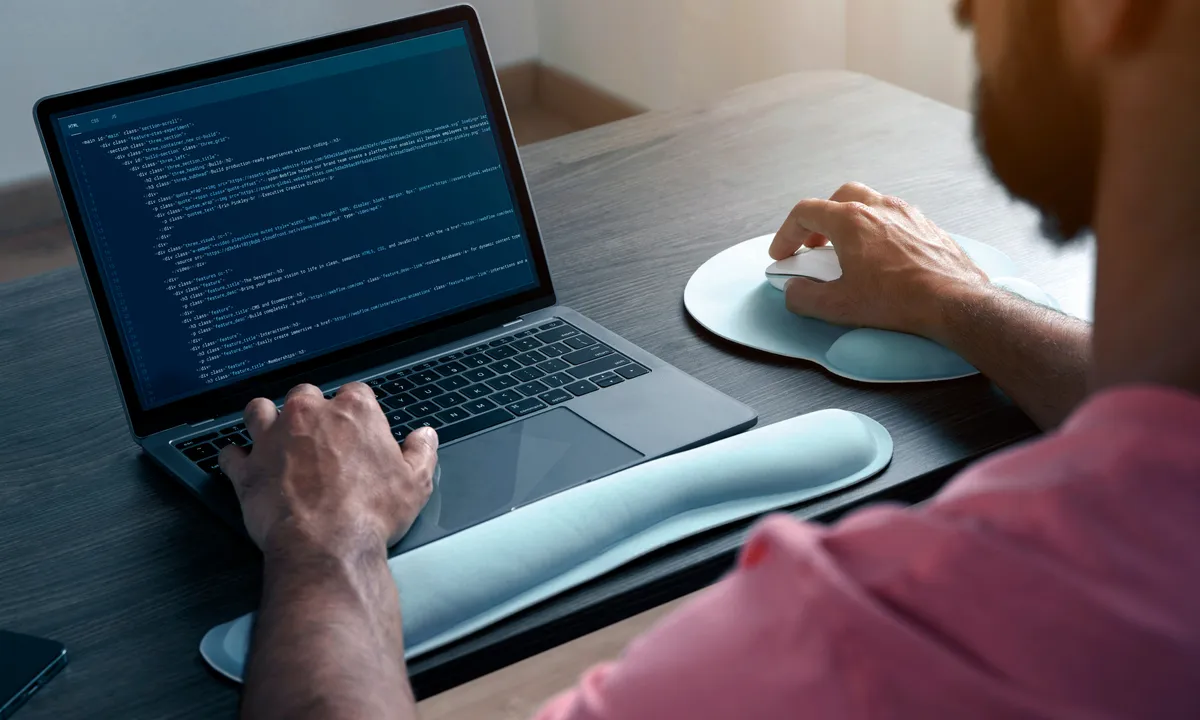 a laptop on a desk with a human hand